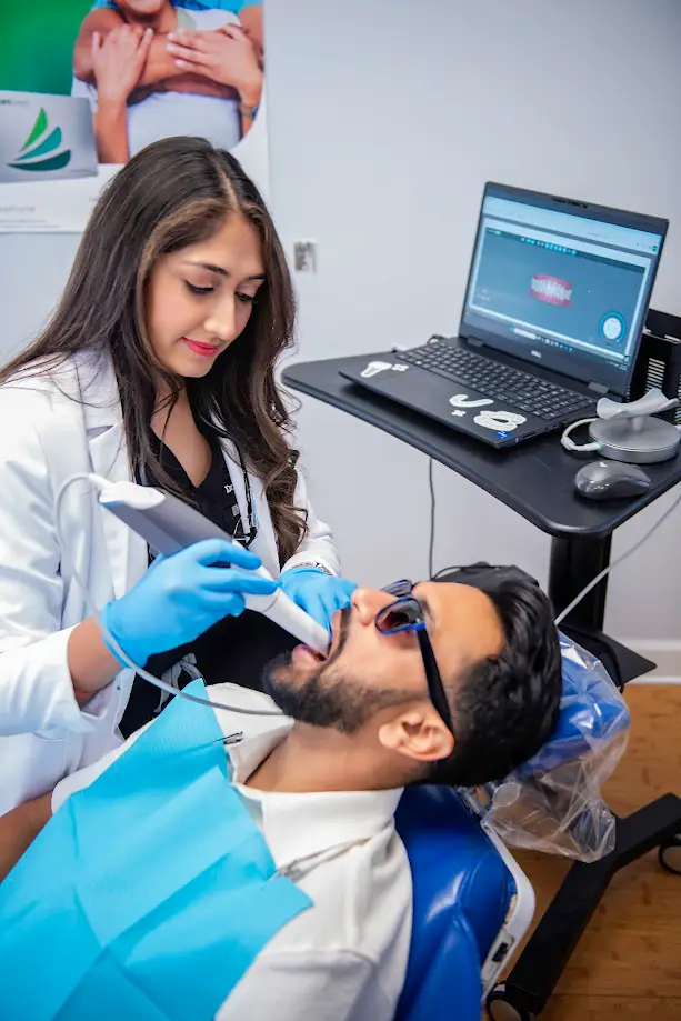 Photo of Dr. Pinky Vanmali using an imaging wand to take a scan of the inside of a patient's mouth.