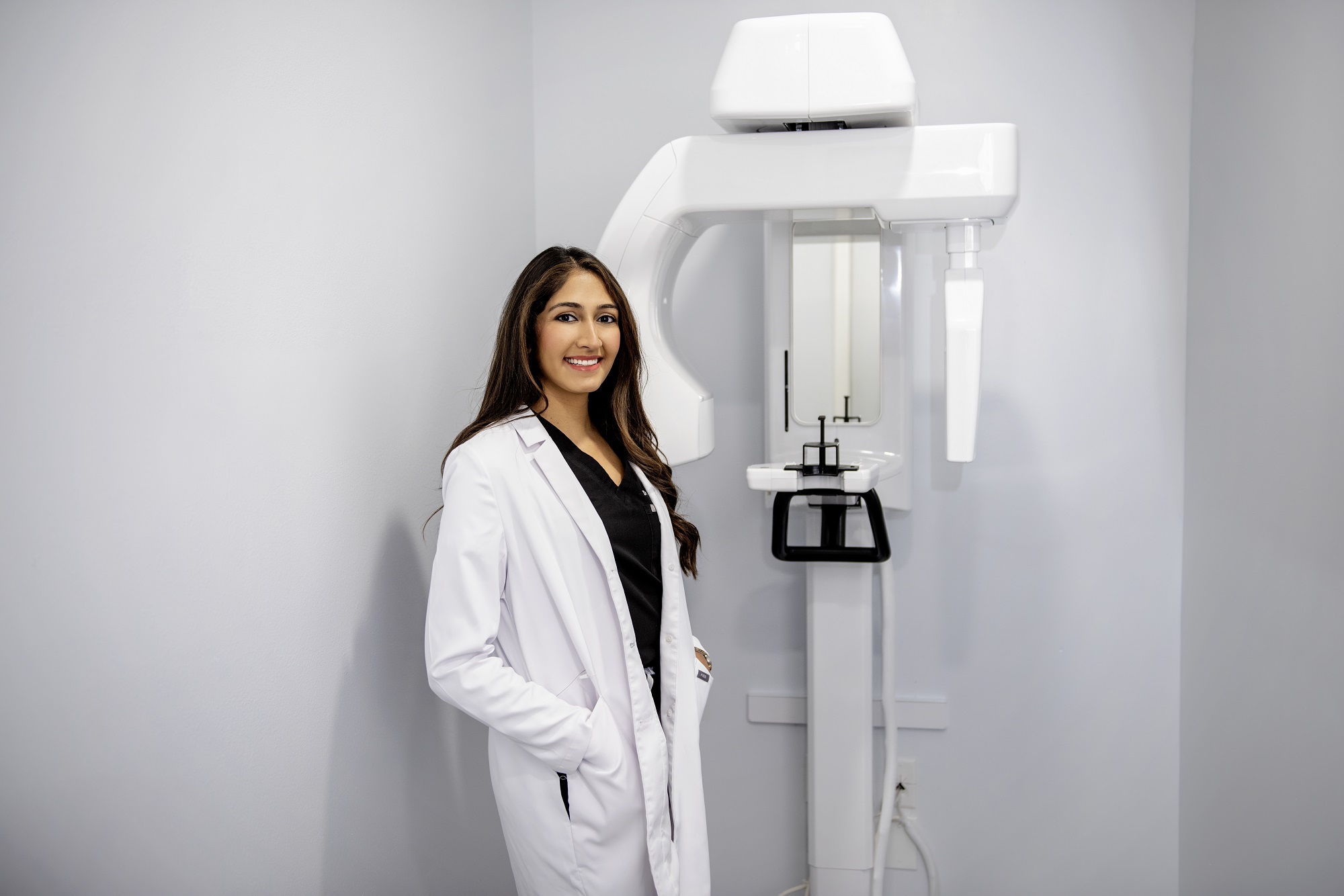 Dr. Pinky Vanmali standing next to a 3D imaging x-ray machine.